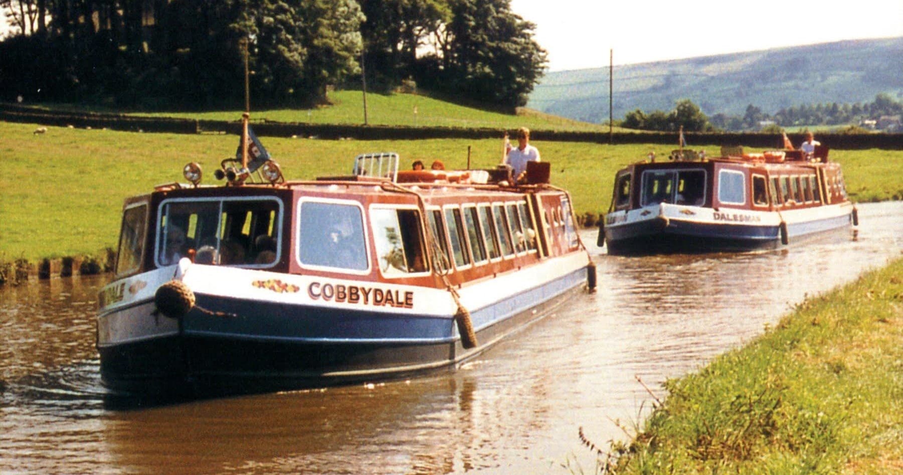 Two canal boats cruising pastoral Yorkshire Dales waterways