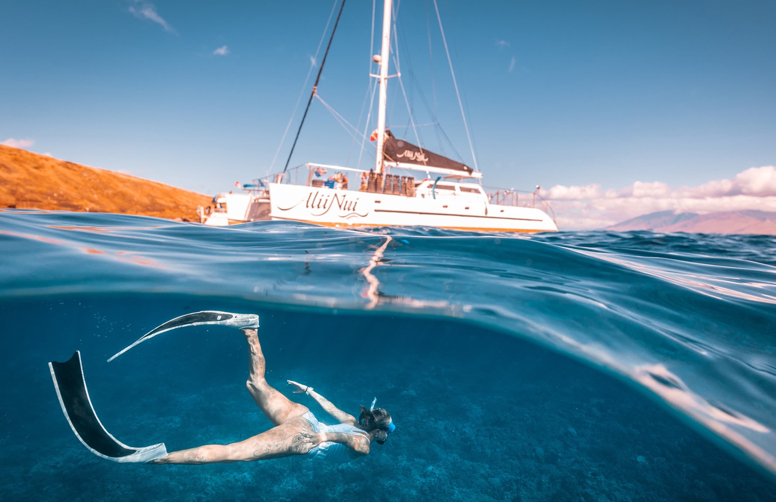 Panoramic shot of sailboat near dramatic Maui sea cliffs