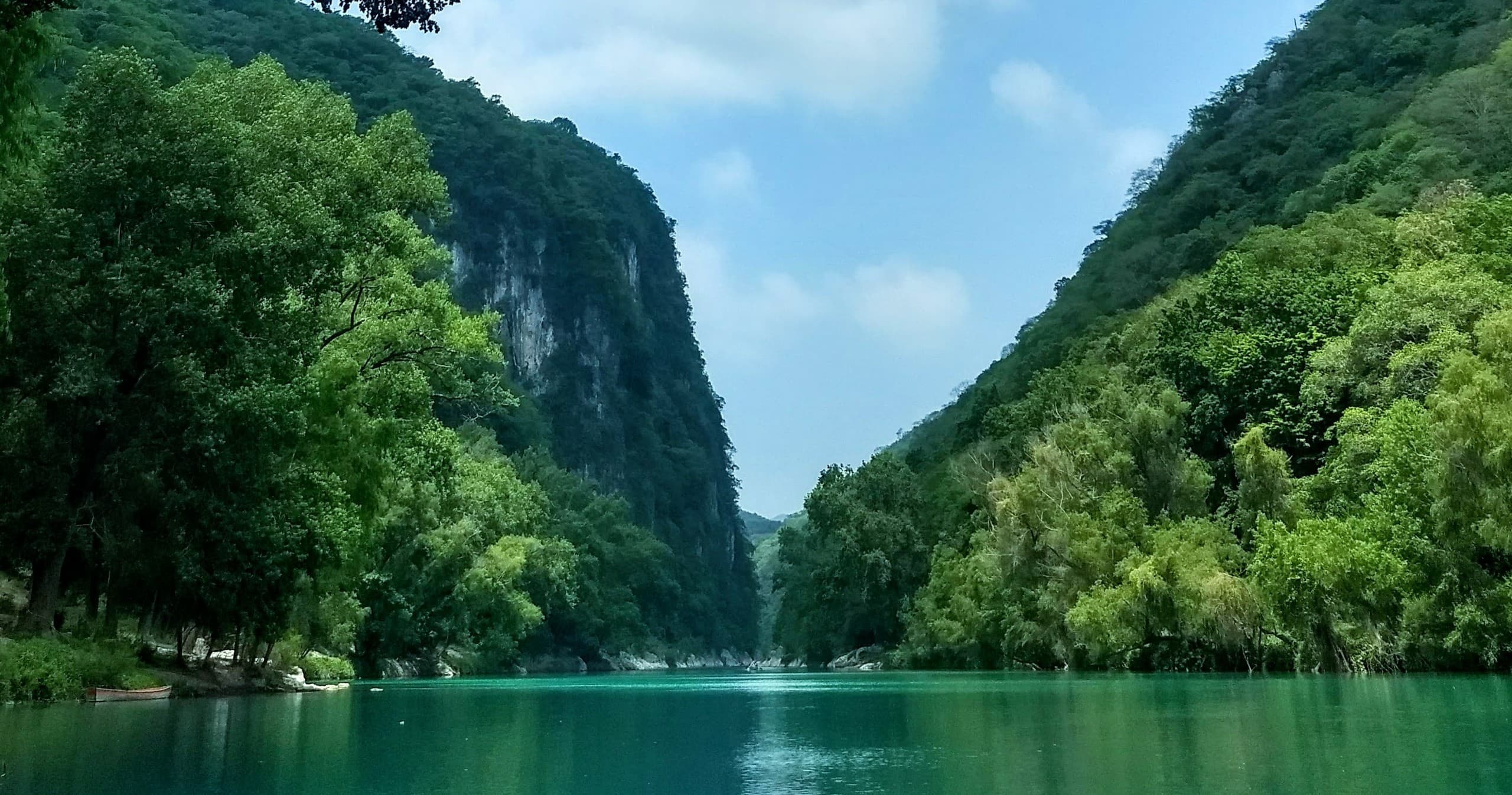 Calm emerald lake framed by towering forested limestone cliffs