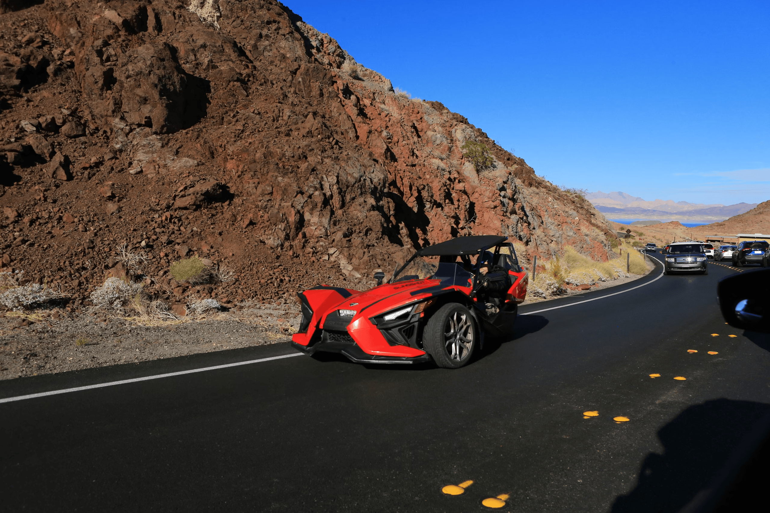 Red Slingshot three-wheeler driving on desert highway
