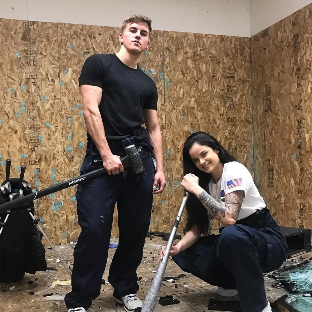 Two participants posing with sledgehammers in indoor smash room