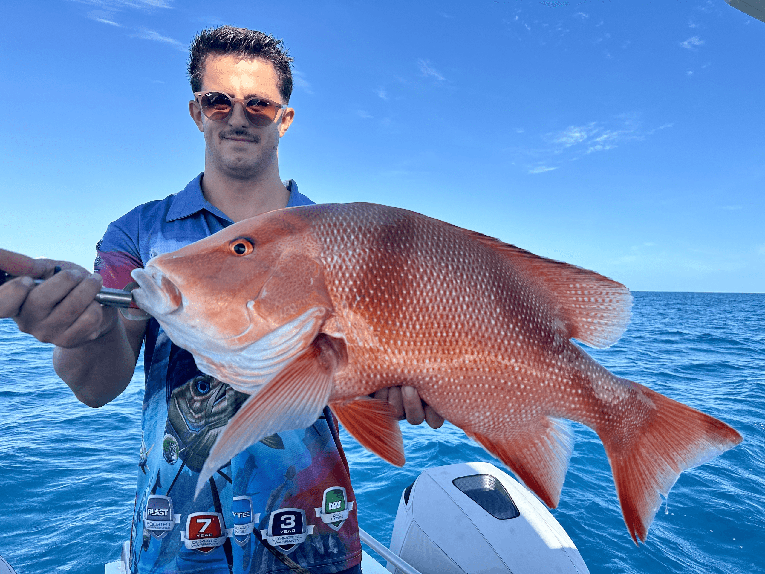 Angler holding large red snapper on deep blue ocean fishing trip