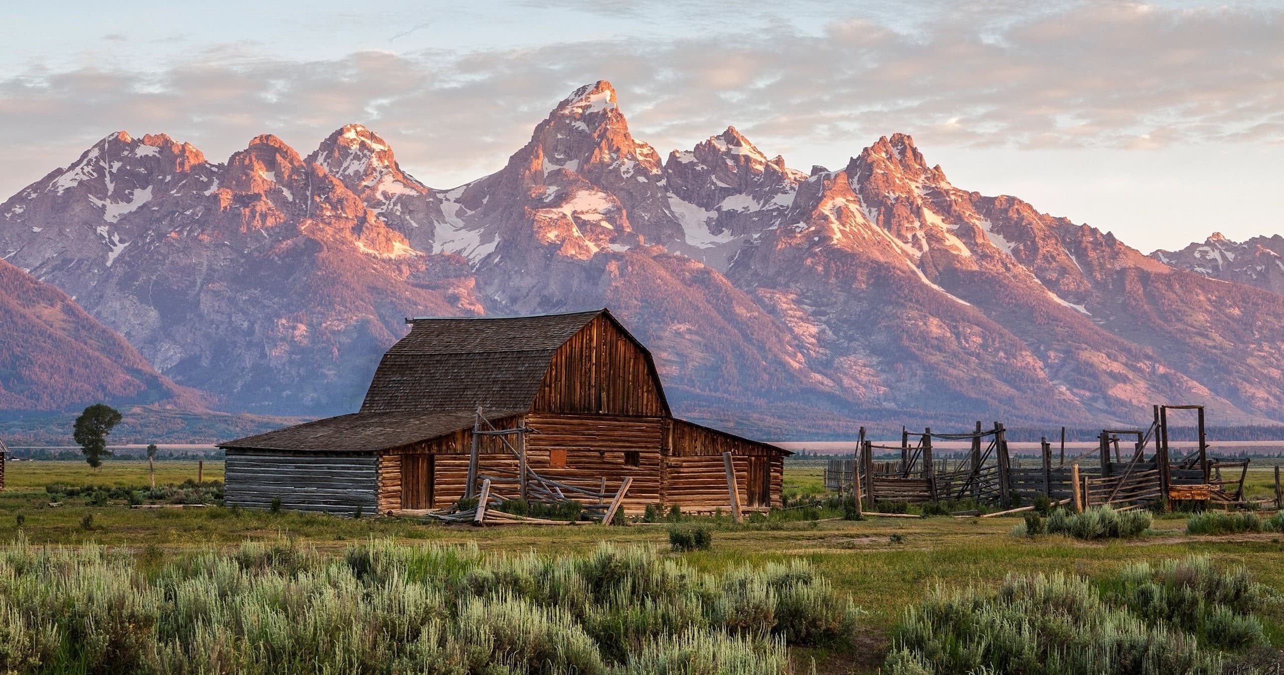 Rustic barn with Grand Teton mountains at sunrise, scenic view