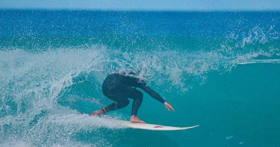 Surfer riding a turquoise barrel wave in open ocean