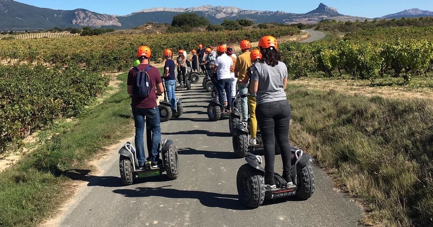 Couples on Segway tour along vineyard paths with clear blue sky