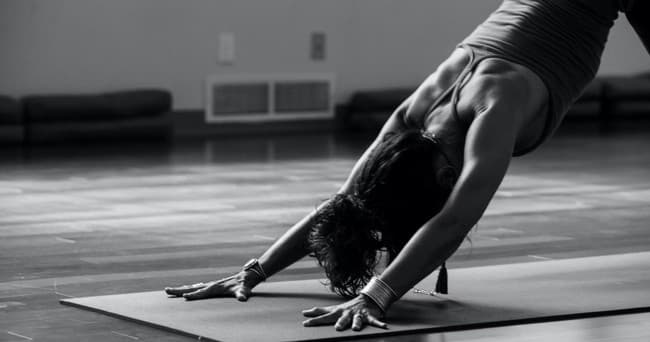 Person practicing downward dog yoga pose on indoor studio mat