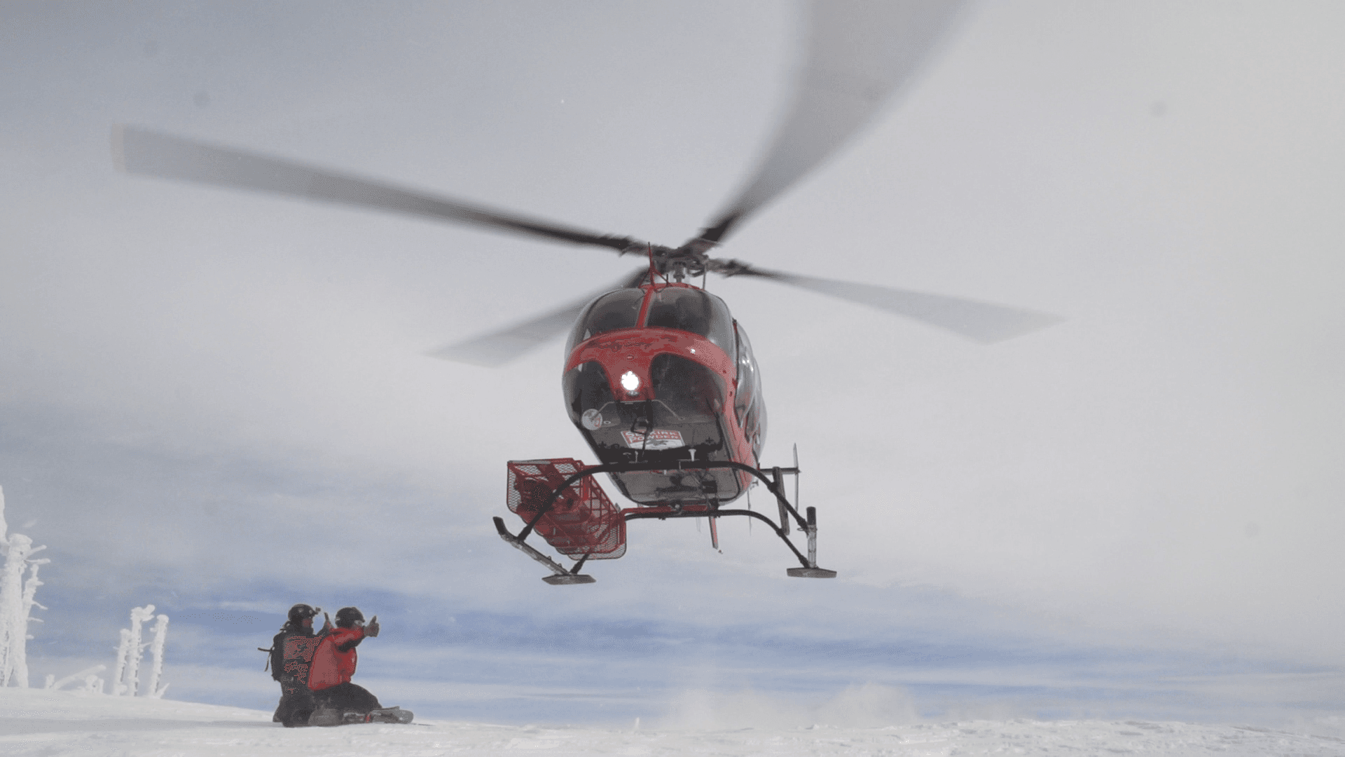 Red helicopter dropping skier into remote snowy backcountry
