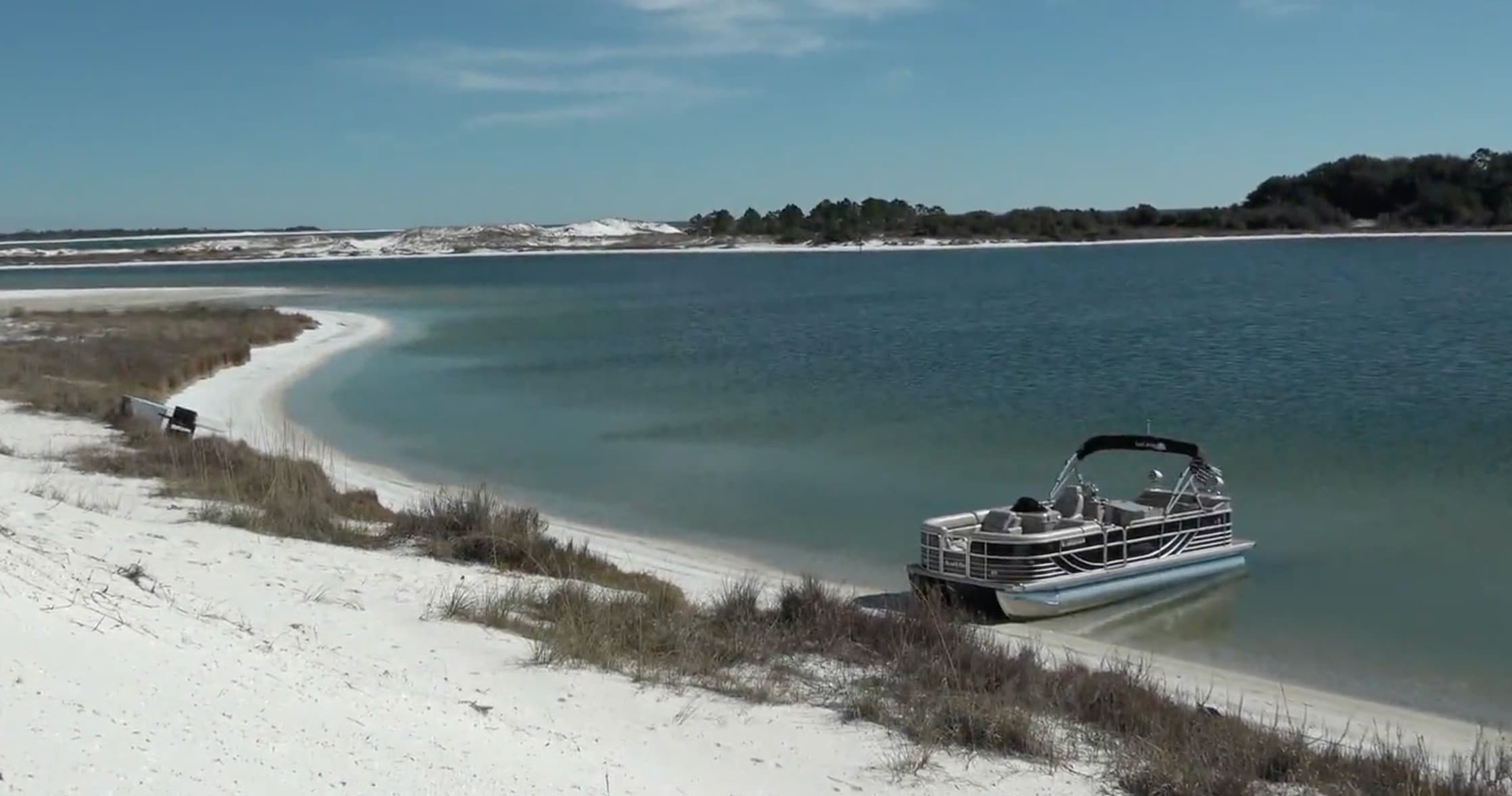 Pontoon boat anchored on white-sand coastal lagoon, scenic beach