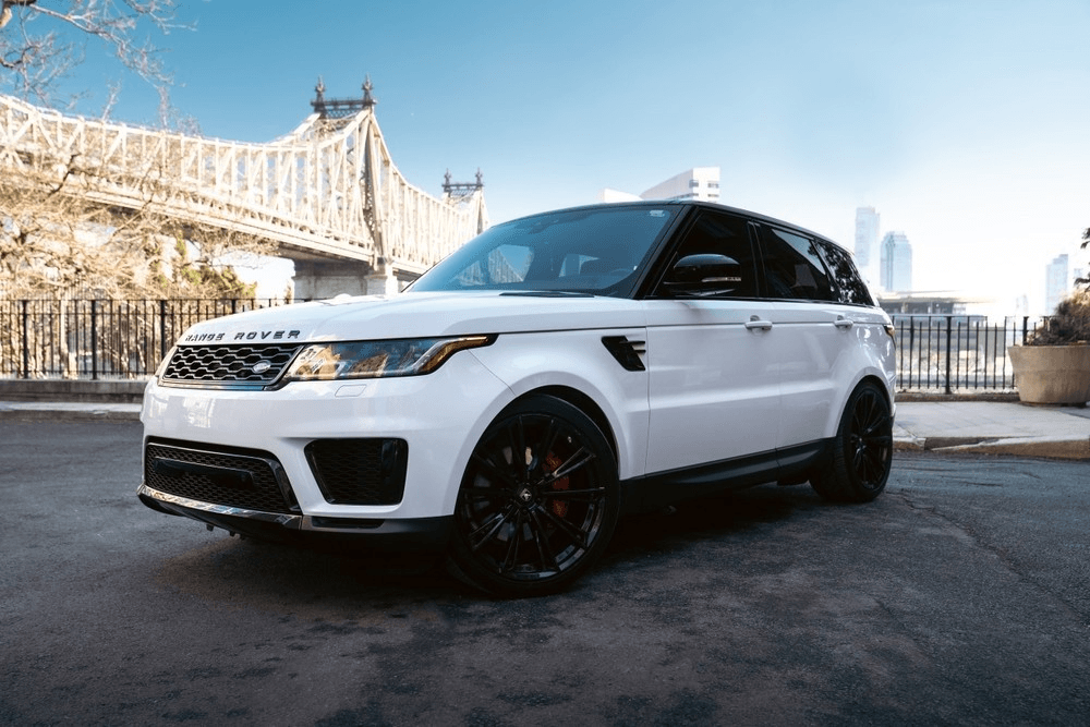 White Range Rover parked by riverside bridge with clear sky