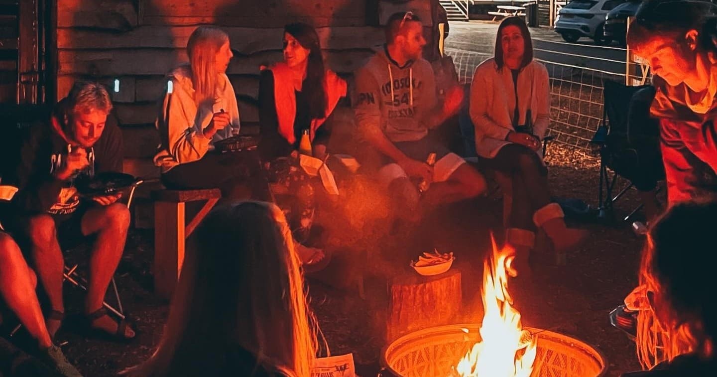Group gathered around campfire at lakeside evening glowing flames