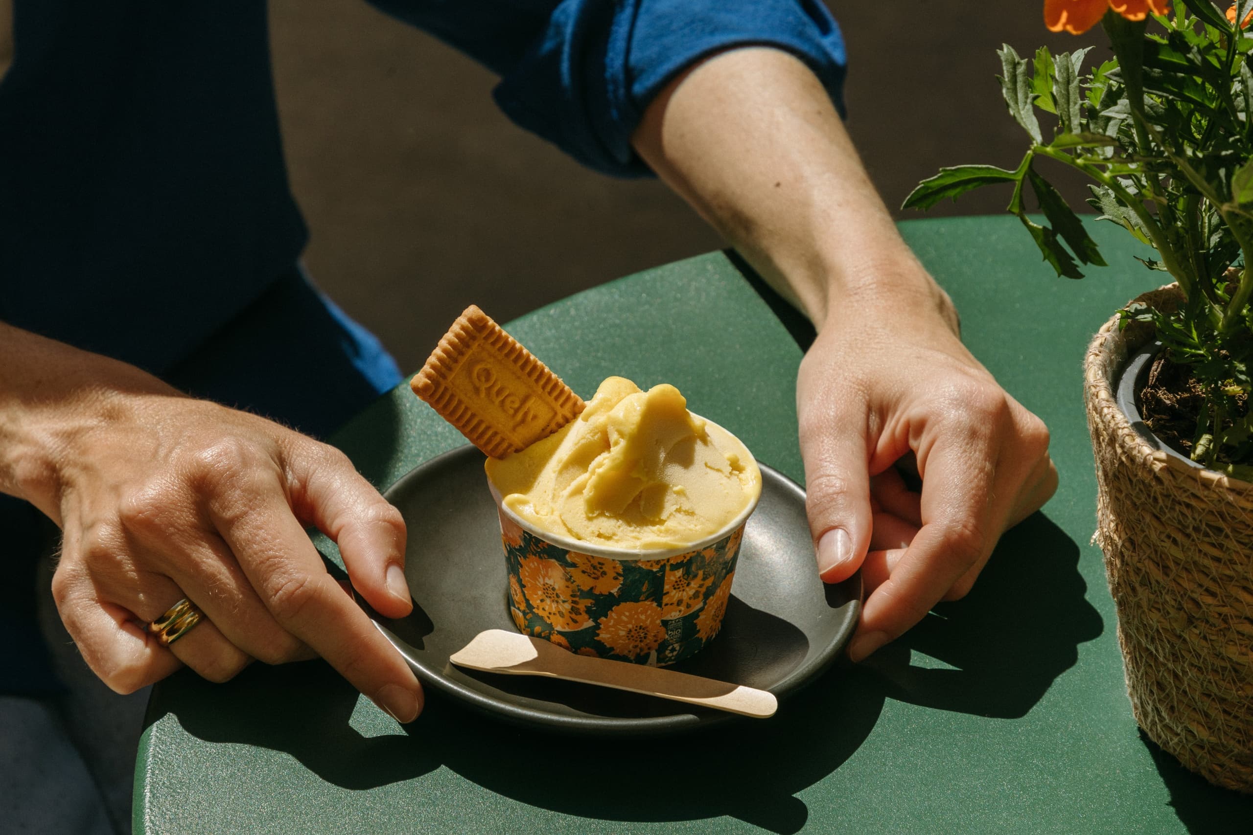 Person enjoying gelato outdoors at cafe table in sunlight