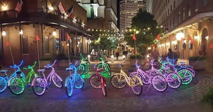 Group of LED-lit bikes parked on urban cobblestone street at night