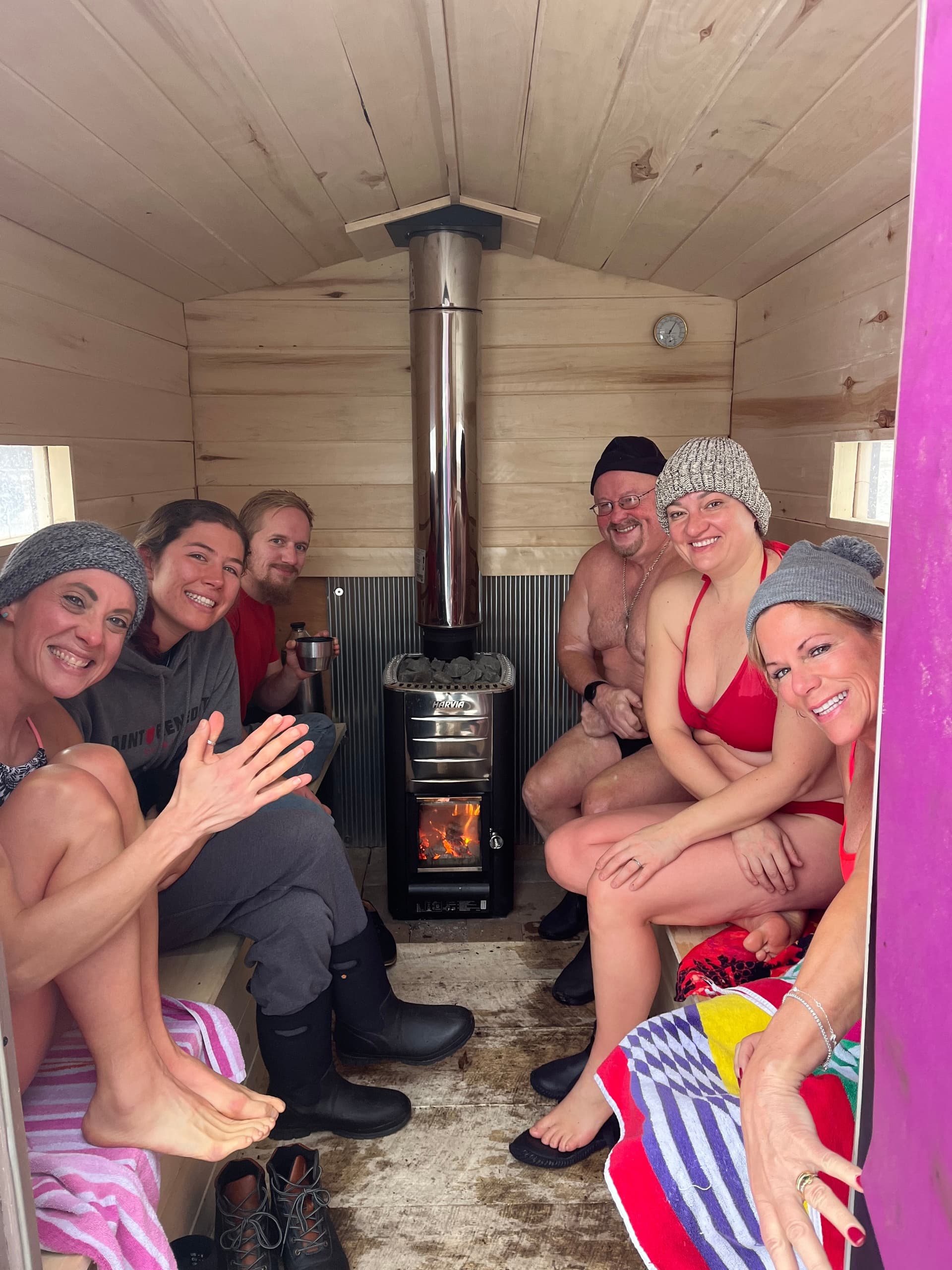 Small group enjoying wood-fired sauna session inside portable cabin