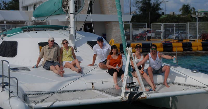 Group lounging on catamaran docked near marina before sailing