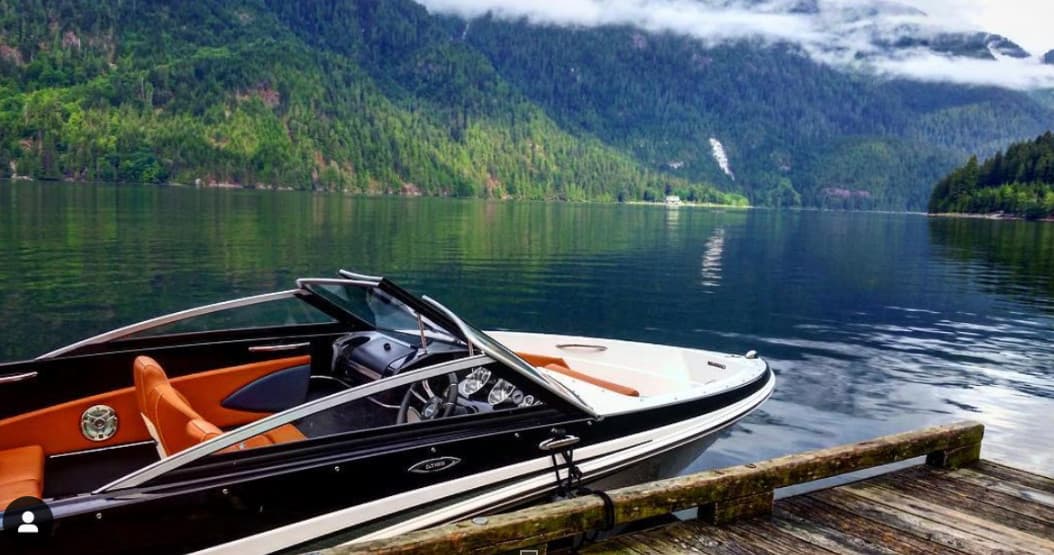 Sleek bowrider moored on glassy alpine fjord with mountains