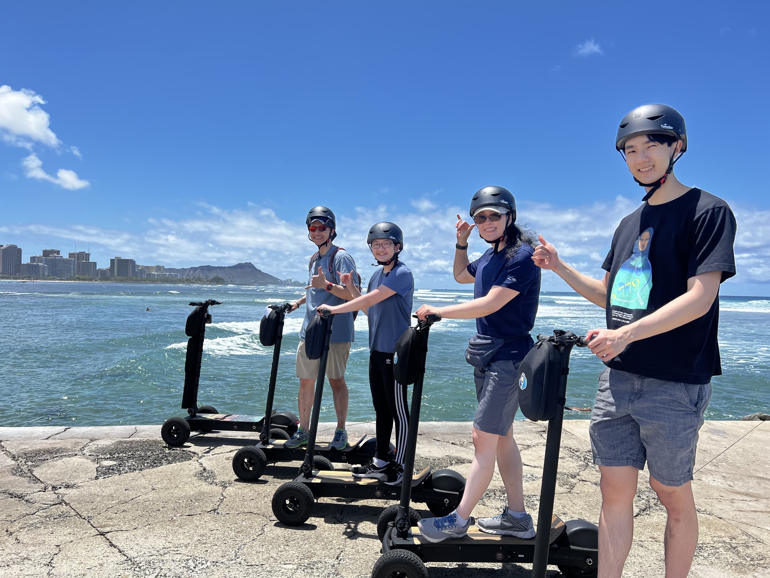 Group on electric scooters along Waikiki waterfront, ocean views