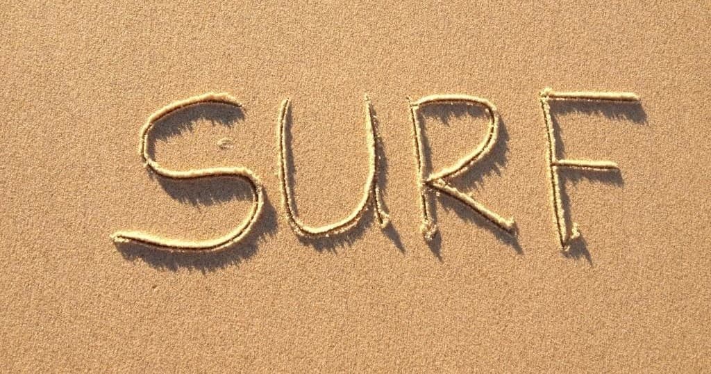 SURF word drawn in beach sand on sunny Gold Coast shore