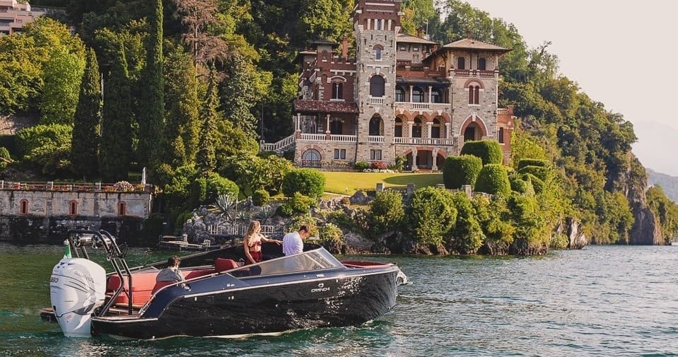Luxury motorboat cruising past villa along scenic shoreline