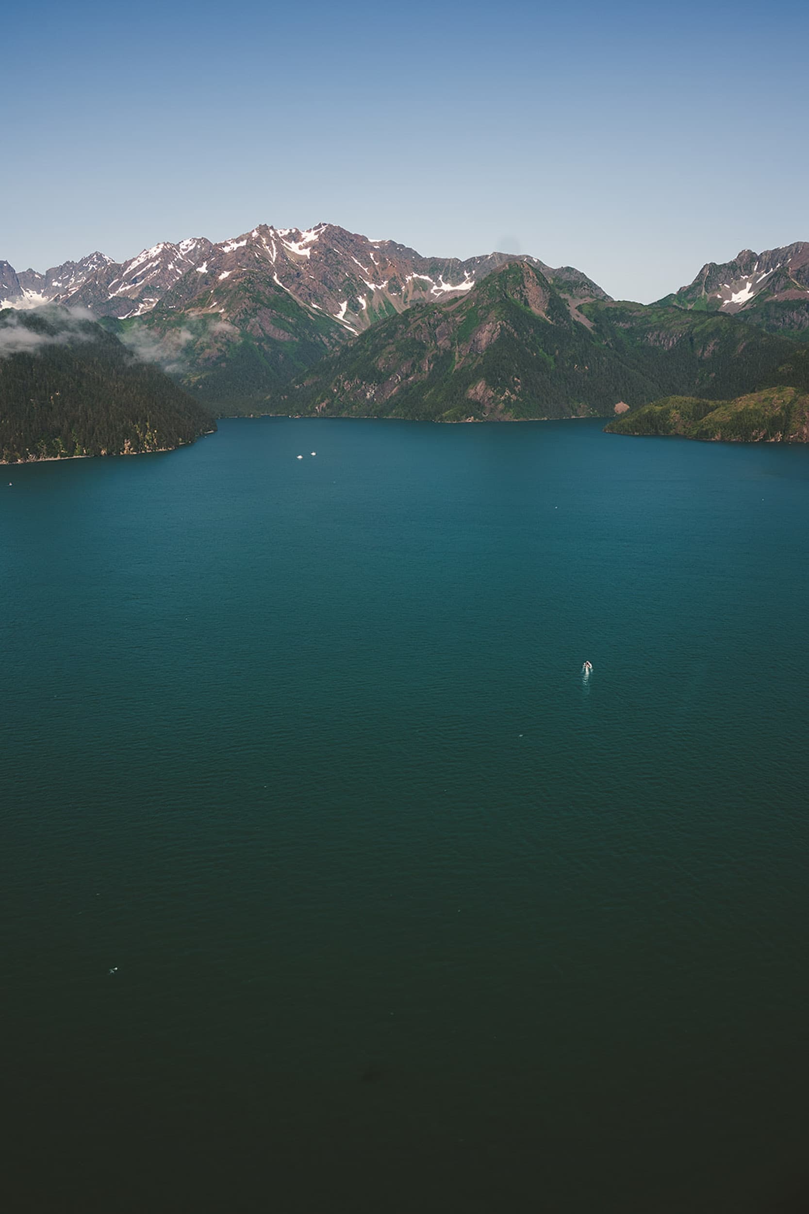 Alpine fjord lake framed by mountain ridges, aerial view
