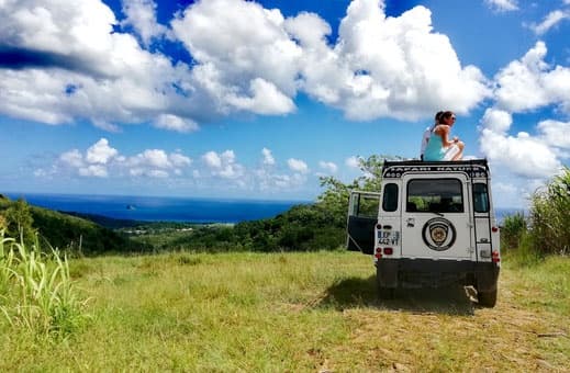Off-road Land Rover overlooking coastal vista, scenic hilltop view