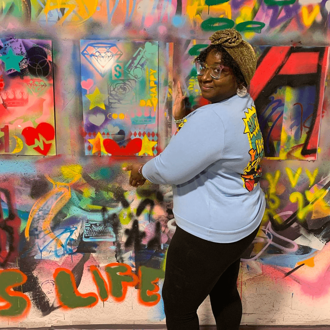 Participant creating colorful graffiti art at indoor spray wall