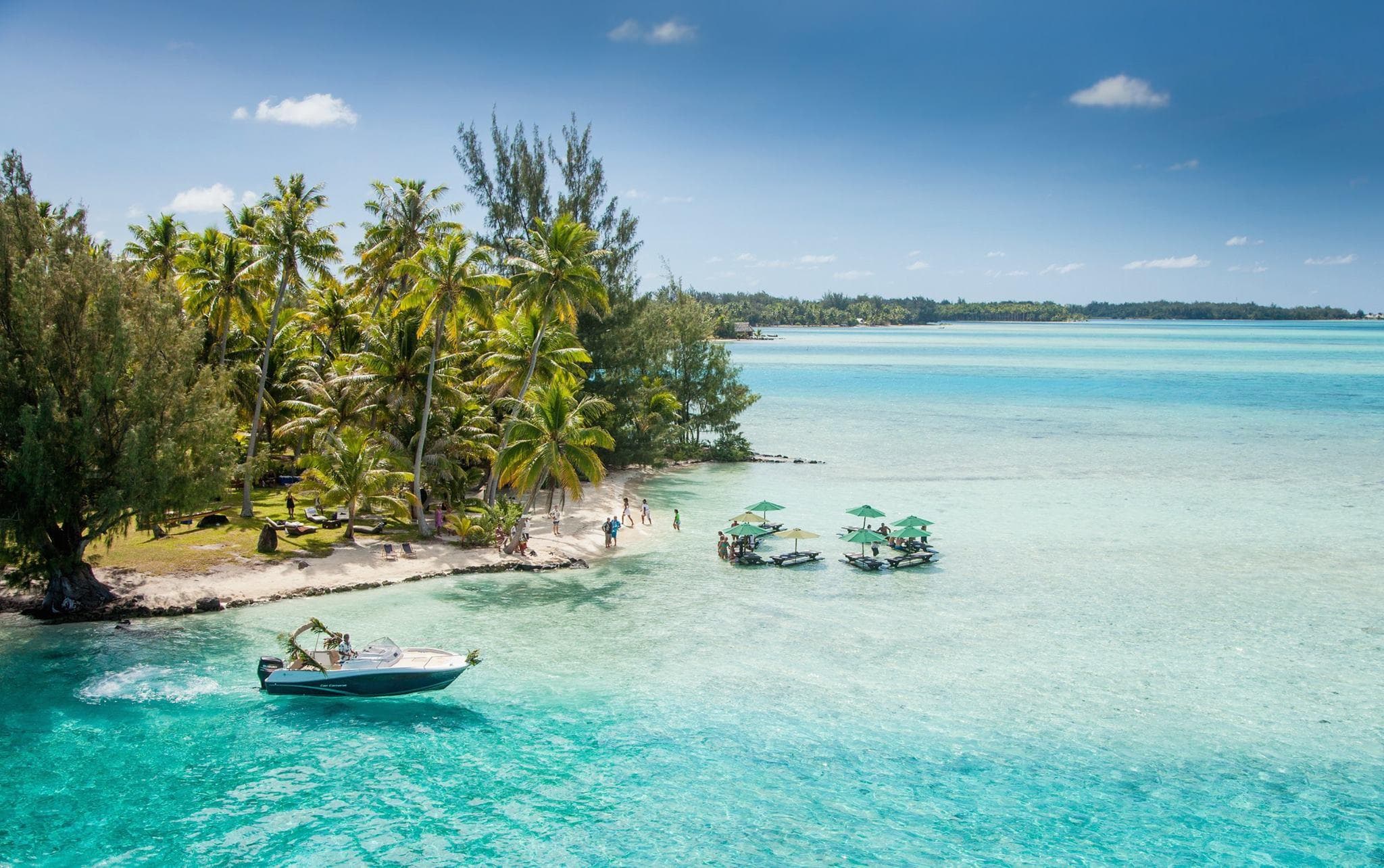 Palm-fringed lagoon with anchored boat and clear turquoise sea