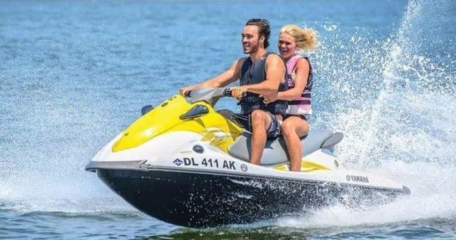 Two riders on a yellow jet ski speeding across coastal waters