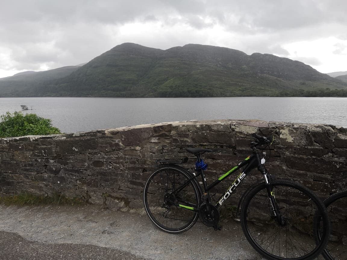 Mountain lake view with parked bike at stone wall in Killarney