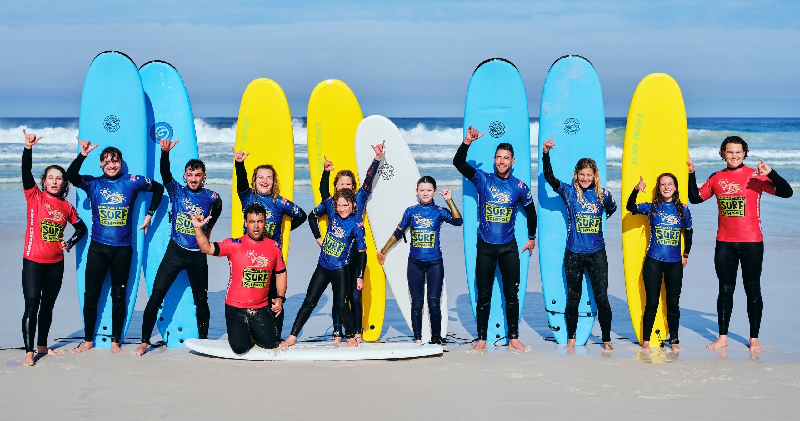 Group of surf students with colorful boards lined up on Margaret River beach