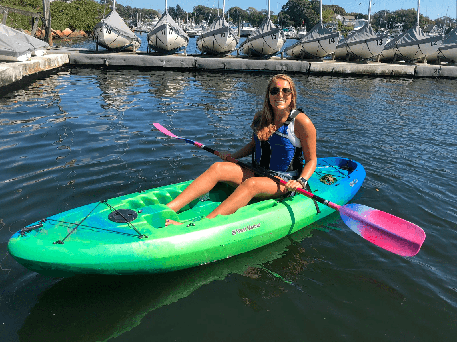Recreational kayaker paddling a green kayak in marina harbor