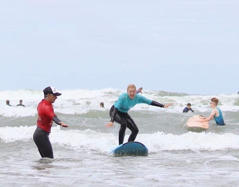 Surfing lesson with instructor coaching student on small waves