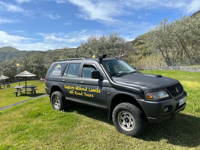 4x4 adventure vehicle parked in mountain meadow by picnic area