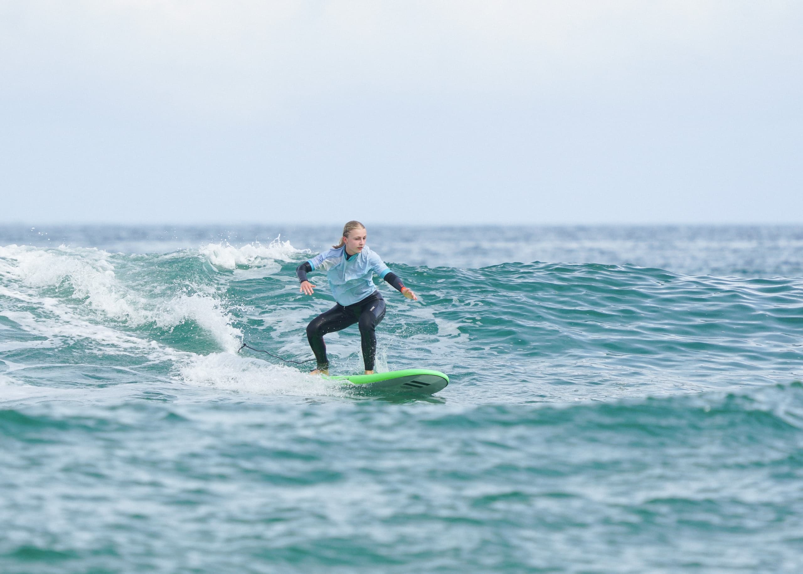 Surfer riding green board on ocean waves off El Cotillo coast