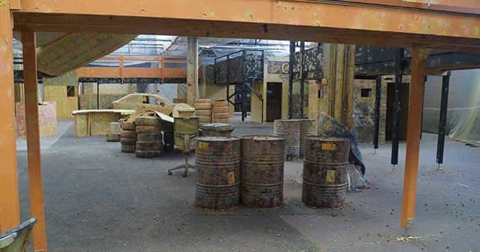 Indoor paintball warehouse course with barrels and open lanes