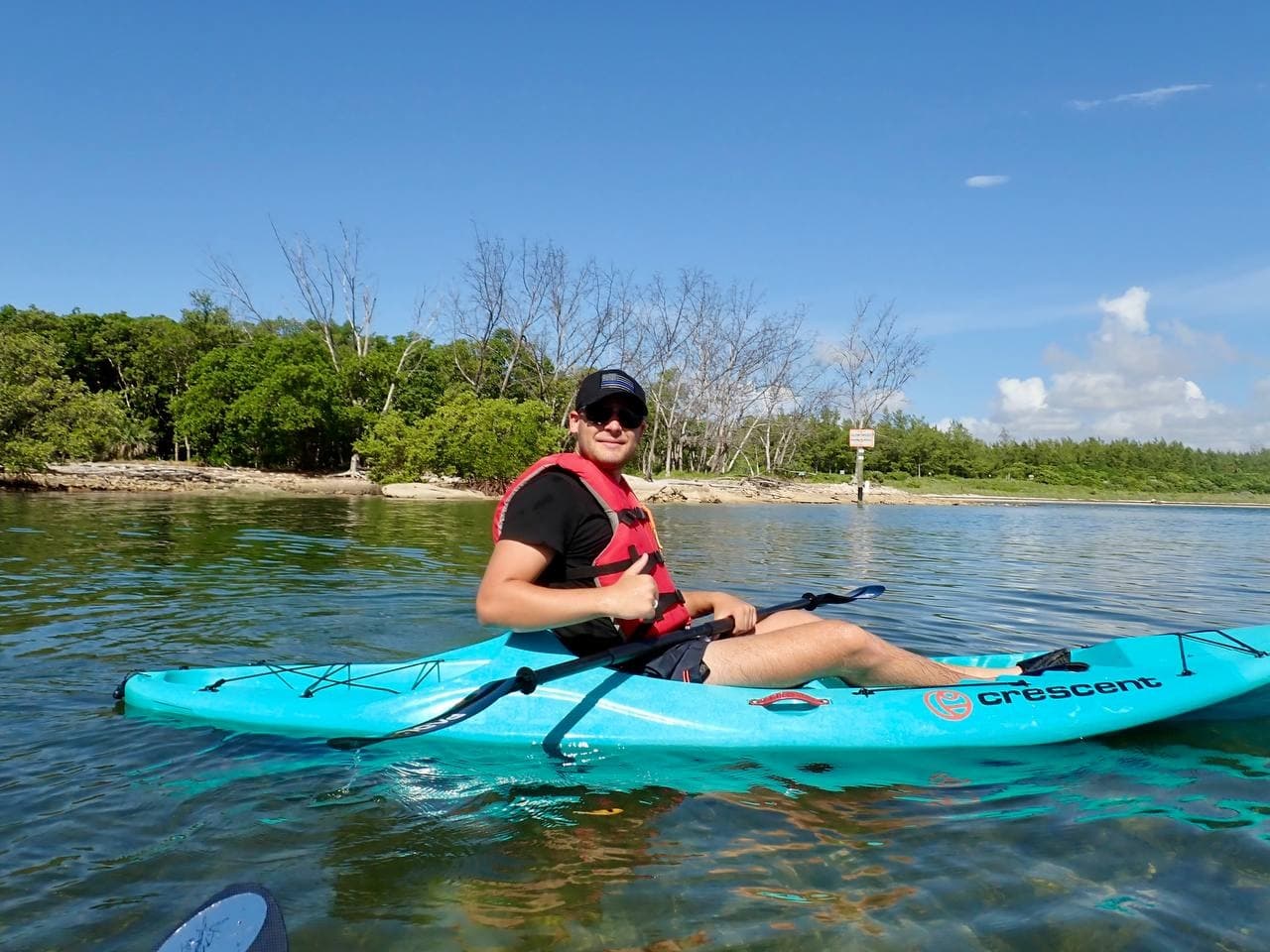 Solo kayaker enjoying turquoise sea near mangroves on sunny day