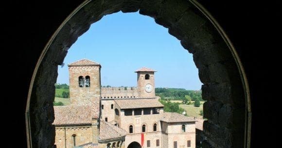 Ancient stone arch framing hilltop Italian castle and valley