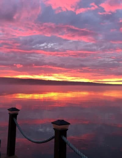 Vibrant pink lake sunset viewed from dock posts and rope