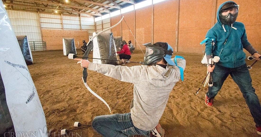 Kneeling archer drawing bow during indoor archery game