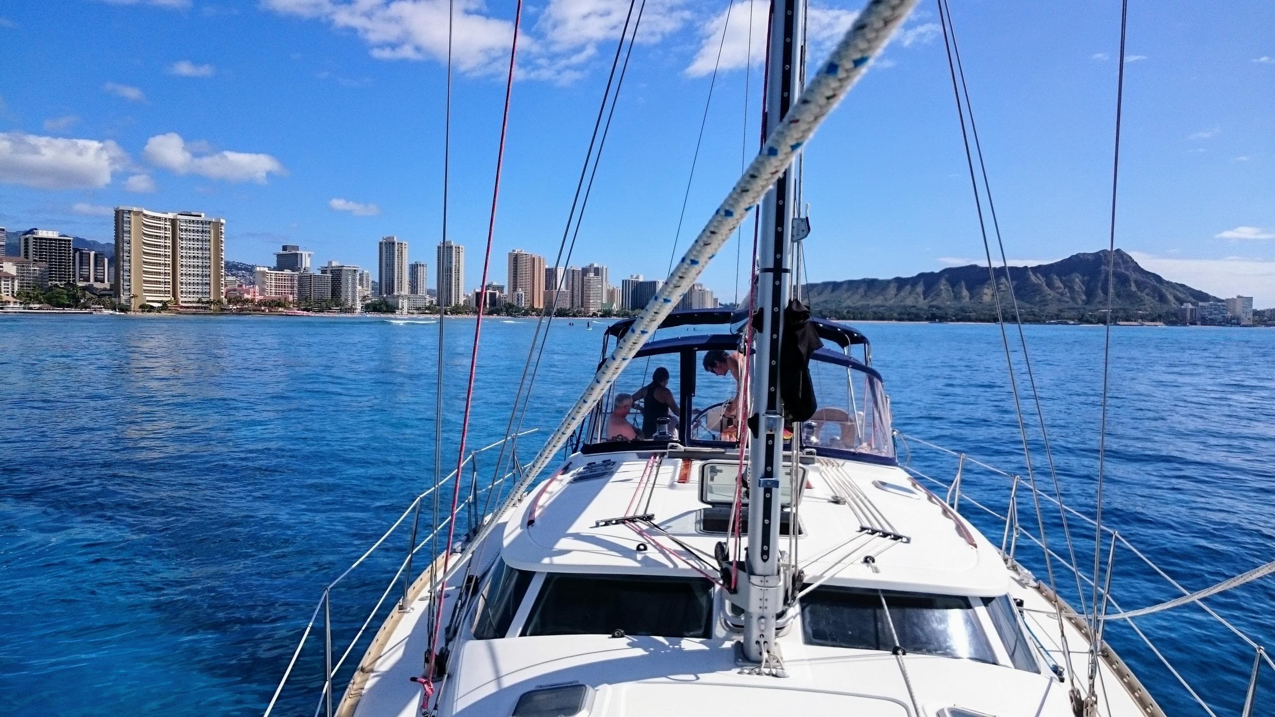 Bow view from sailboat toward coastal skyline and calm harbor