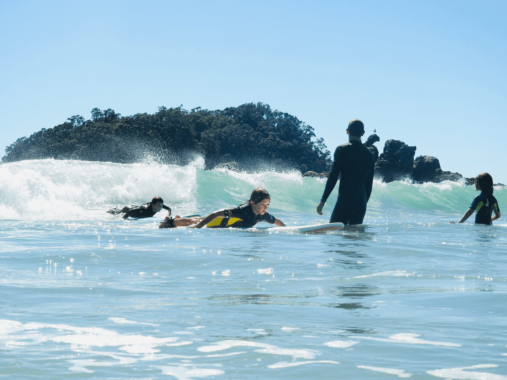 Group of surfers in shallow ocean waves near coastal rocks