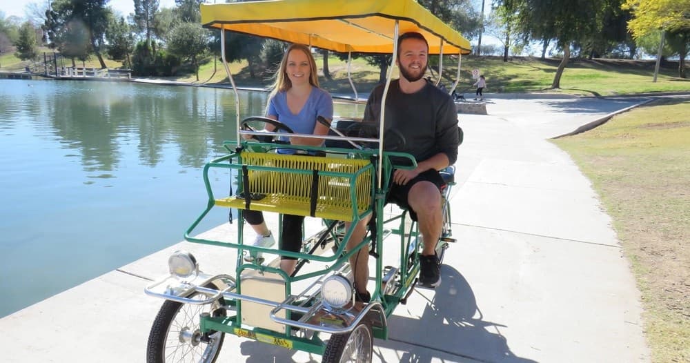 Two-person surrey bike by lake pathway offering casual outdoor ride