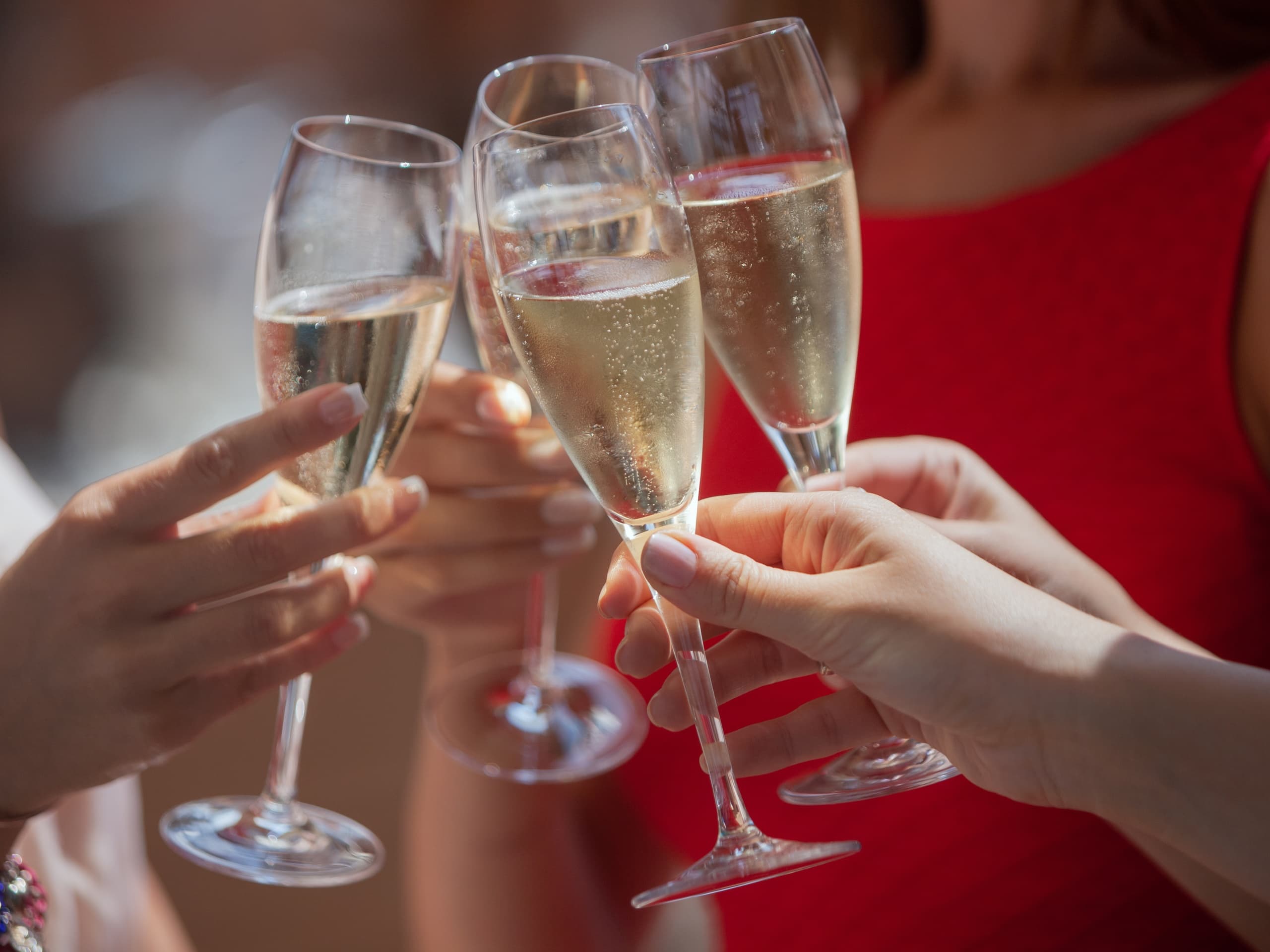 Close up champagne toast at indoor celebration, drinks clinking