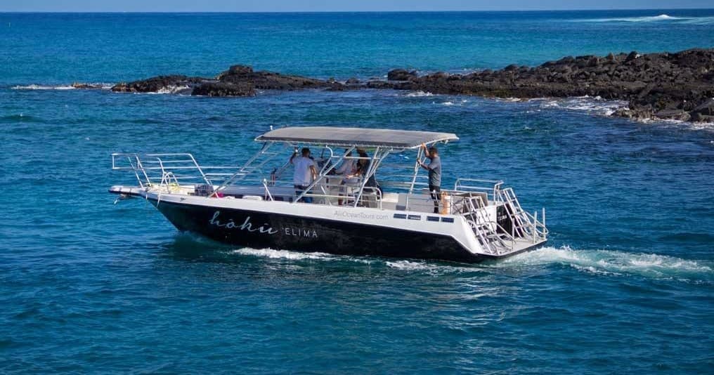Ocean tour boat sailing along blue coastal waters under clear sky