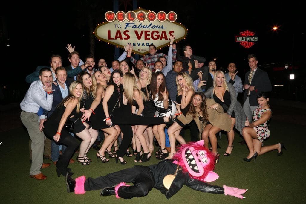 Large bachelorette group posing at Las Vegas welcome sign at night