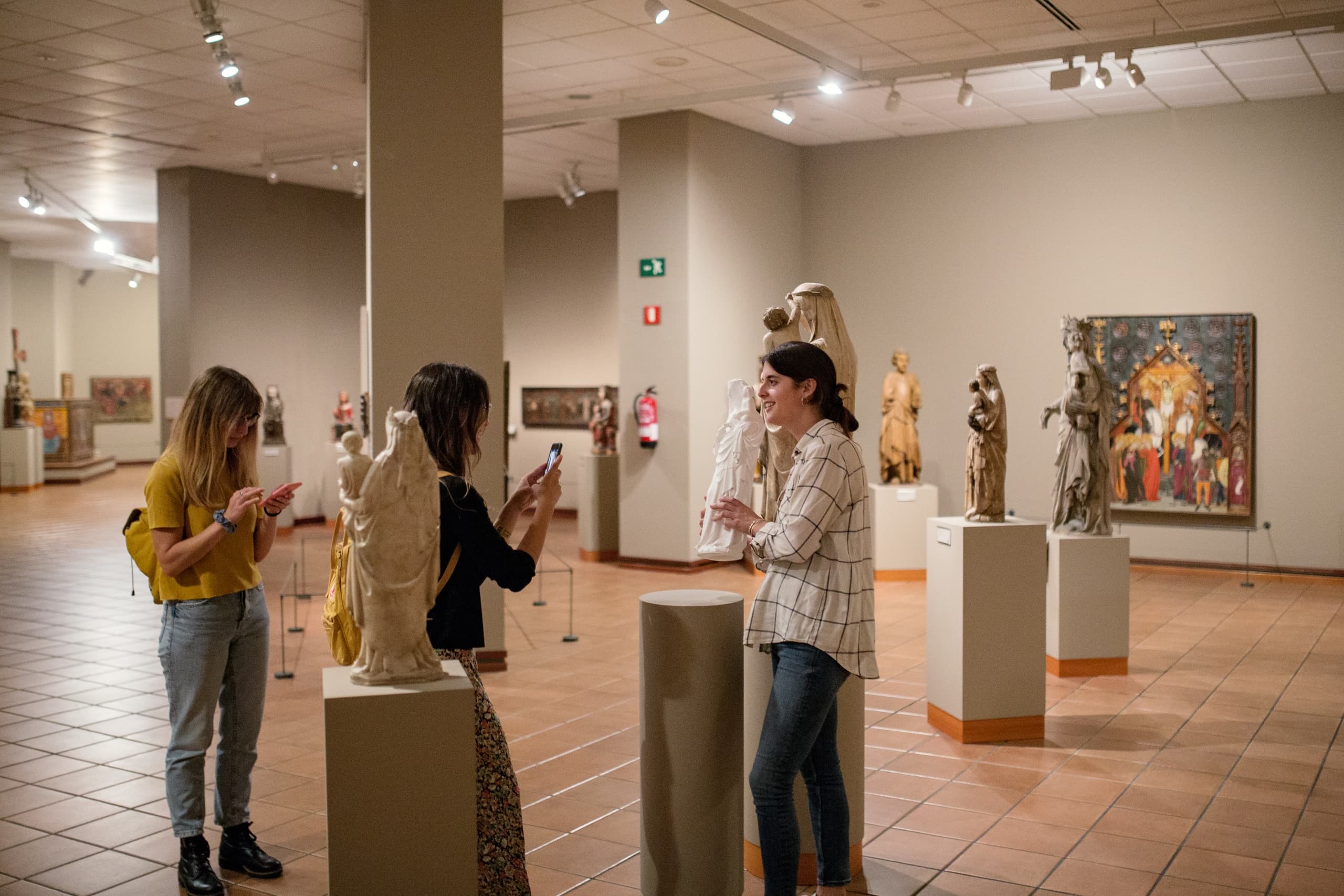 Group viewing medieval sculptures in museum gallery space