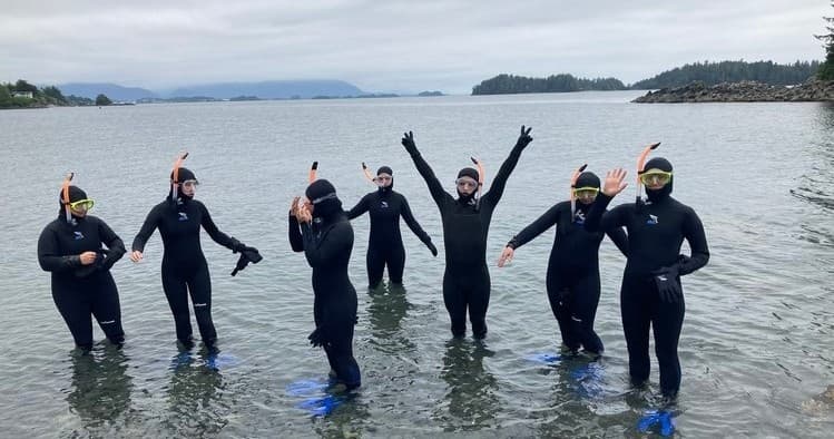Group snorkeling in wetsuits in a coastal inlet near islands