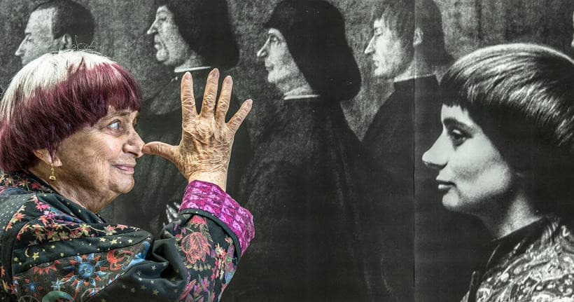 Elderly guide gesturing to historical film portraits in museum exhibit