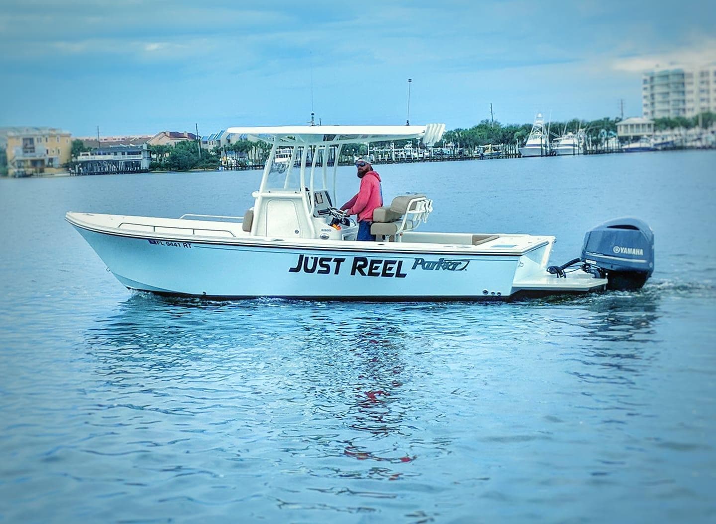 Small charter boat 'Just Reel' fishing near coastal harbor