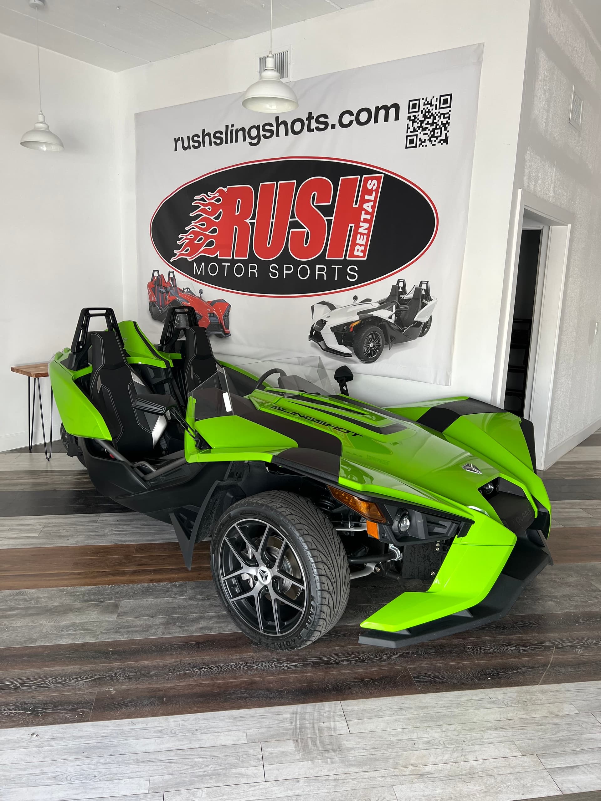 Green Slingshot displayed indoors in showroom for vehicle rental