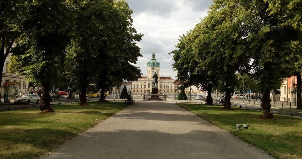 Tree-lined boulevard leading to historic building in Berlin park